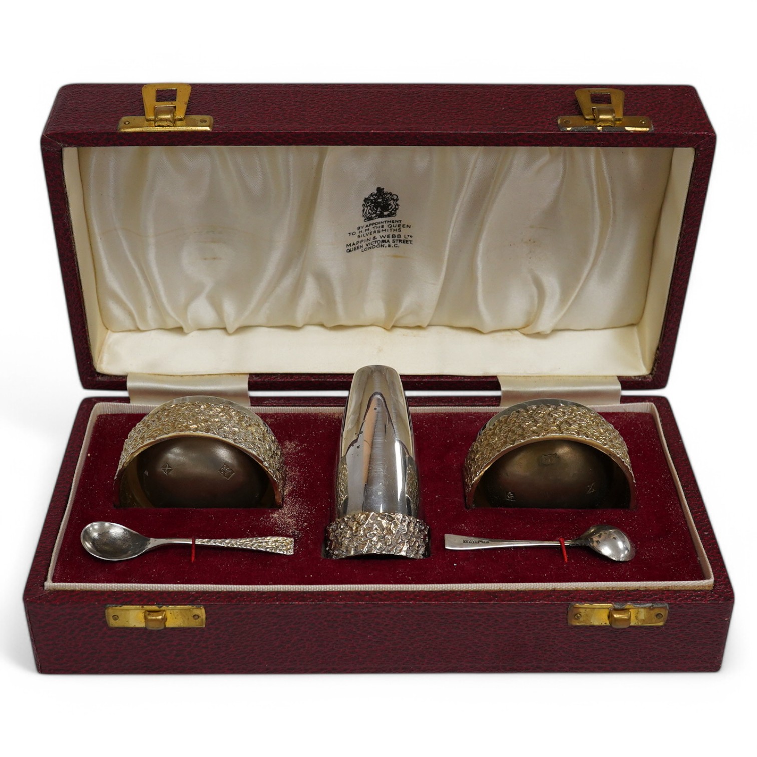 A cased Elizabeth II parcel gilt silver three piece cruet set, with textured band and two matching spoons, by Mappin & Webb, Birmingham, 1972, pepper 72mm. Condition - fair to good